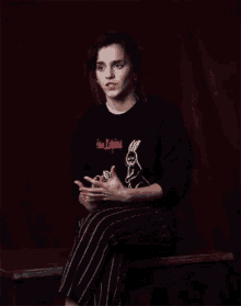 a woman wearing a black sweater with two rabbits on it is sitting on a bench with her hands outstretched