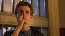 a man in a leather jacket holds his nose to his mouth