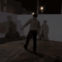 a man in a white shirt is standing in the dark