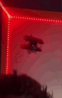 a toy airplane is flying through a red lighted room .