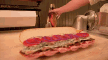 a sandwich is being prepared on a cutting board by a person