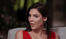 a woman in a red dress is sitting on a couch .