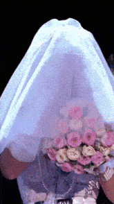 a woman in a wedding dress is holding a bouquet of pink flowers