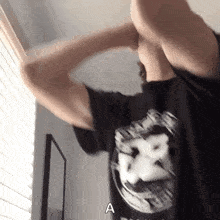 a person wearing a black shirt with the letter a on it is standing in front of a window .