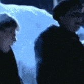 two people are standing next to each other in front of a snowy field .