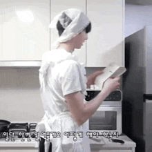 a man in a white apron is standing in a kitchen .