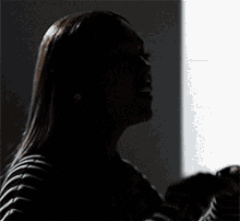 a woman in a black and white striped sweater is standing in front of a wall with her hands in the air .