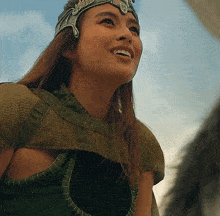 a woman wearing a crown and a green top smiles