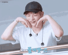 a young man wearing a hat and headphones is making a heart with his hands .