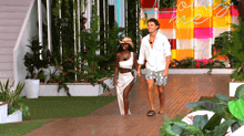 a man and a woman walking in front of a love me sign