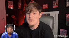 a man wearing headphones and a blue adidas shirt looks at another man in front of a screen that says gifrun.com