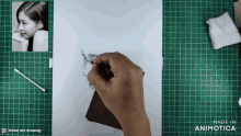 a person is drawing a picture of a girl on a green cutting board made by animatica