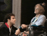 a man is kneeling down next to a woman in a wheelchair