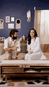 a man and a woman are sitting on a couch and the man is spraying the woman with a spray bottle