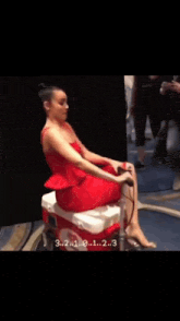 a woman in a red dress is sitting on a cooler with the number 3 on it