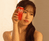 a woman holding a can of coca cola original