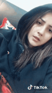 a woman wearing a black hoodie has a tiktok logo on the bottom