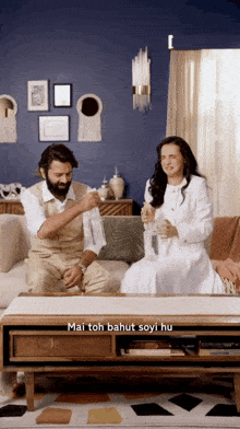 a man and a woman are sitting on a couch in a living room with mai toh bahut soyi hu written in the corner