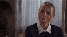 a woman in a blue shirt and white collar smiles