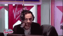 a man wearing headphones is sitting in front of a microphone in a studio .