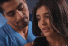 a man and a woman are looking at each other . the man is wearing a blue scrub top .