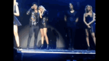 a group of people are standing on a stage and one of them is holding another woman 's hand