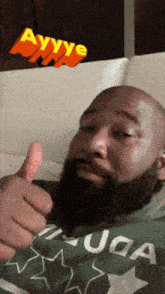 a man with a beard is giving a thumbs up in front of a sign that says ayyye
