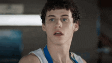 a young man with curly hair is wearing a blue medal around his neck