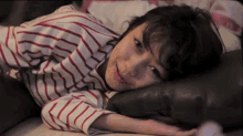 a woman in a striped shirt laying on a bed