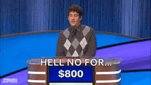 a man is standing in front of a podium on a jeopardy game show .
