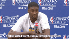 a man speaking into a microphone in front of a wall that says ' nba tv ' on it