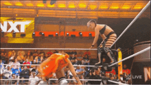 a female wrestler is jumping over another wrestler in front of a sign that says nxt