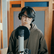 a man wearing glasses and headphones stands in front of a microphone with the letter s on it