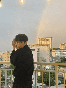 a young man is taking a picture of a rainbow in the sky