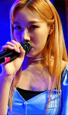 a woman is singing into a microphone while wearing a blue dress
