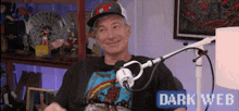 a man is sitting in front of a microphone with the words dark web on the bottom right .