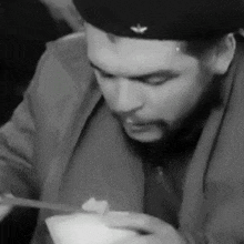 a man with a beard is eating food with chopsticks .