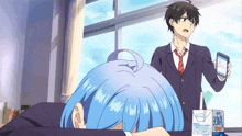 a boy holding a cell phone stands next to a girl laying on the floor with a box that says bona on it