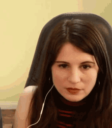 a young woman is sitting in a chair wearing headphones and looking at the camera .