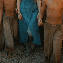 a woman in a blue dress is walking with a group of young men