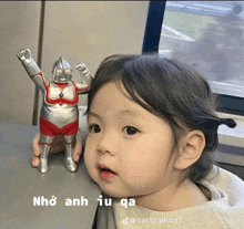 a little girl is looking at a toy that says nho anh iu qua