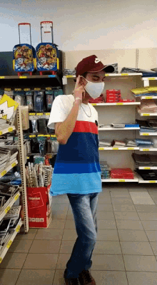a man wearing a mask stands in a store talking on a phone