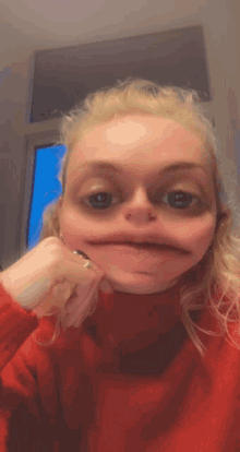 a woman in a red sweater is making a face with her hand on her chin