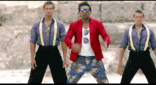 a man wearing sunglasses and a red jacket is dancing with two other men