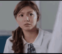 a girl in a school uniform is making a funny face .