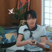 a young man is sitting in front of a television playing a video game .