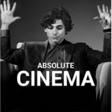 a man in a suit is sitting in a chair with his hands in the air and the words absolute cinema below him