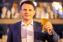 a man in a suit holds a glass of beer in his hand