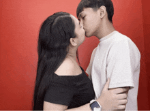 a man and woman kissing in front of a red background