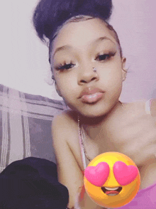 a girl with a nose ring is taking a selfie with a heart shaped emoji behind her